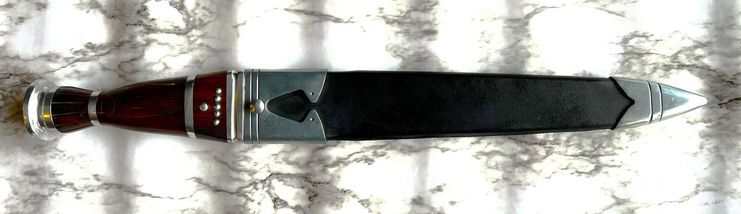 Scottish Long Dirk with Damascus blade and ebony grip on display against a marble background.