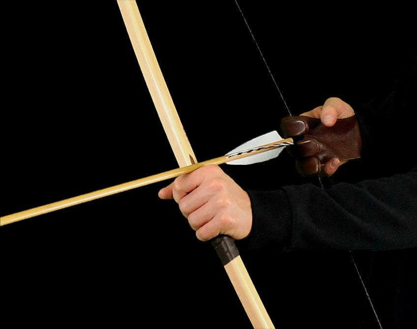How Medieval Archery Changed History: close-up of a hand gripping an arrow on a bow for archery practice.