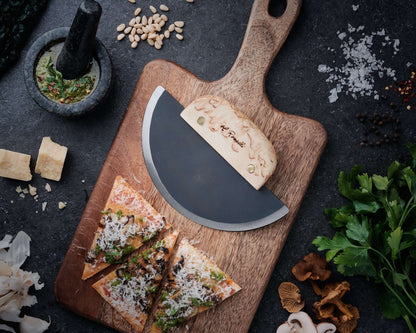 Roselli R740 The Ulu Knife on a wooden cutting board with pizza slices and ingredients around it.