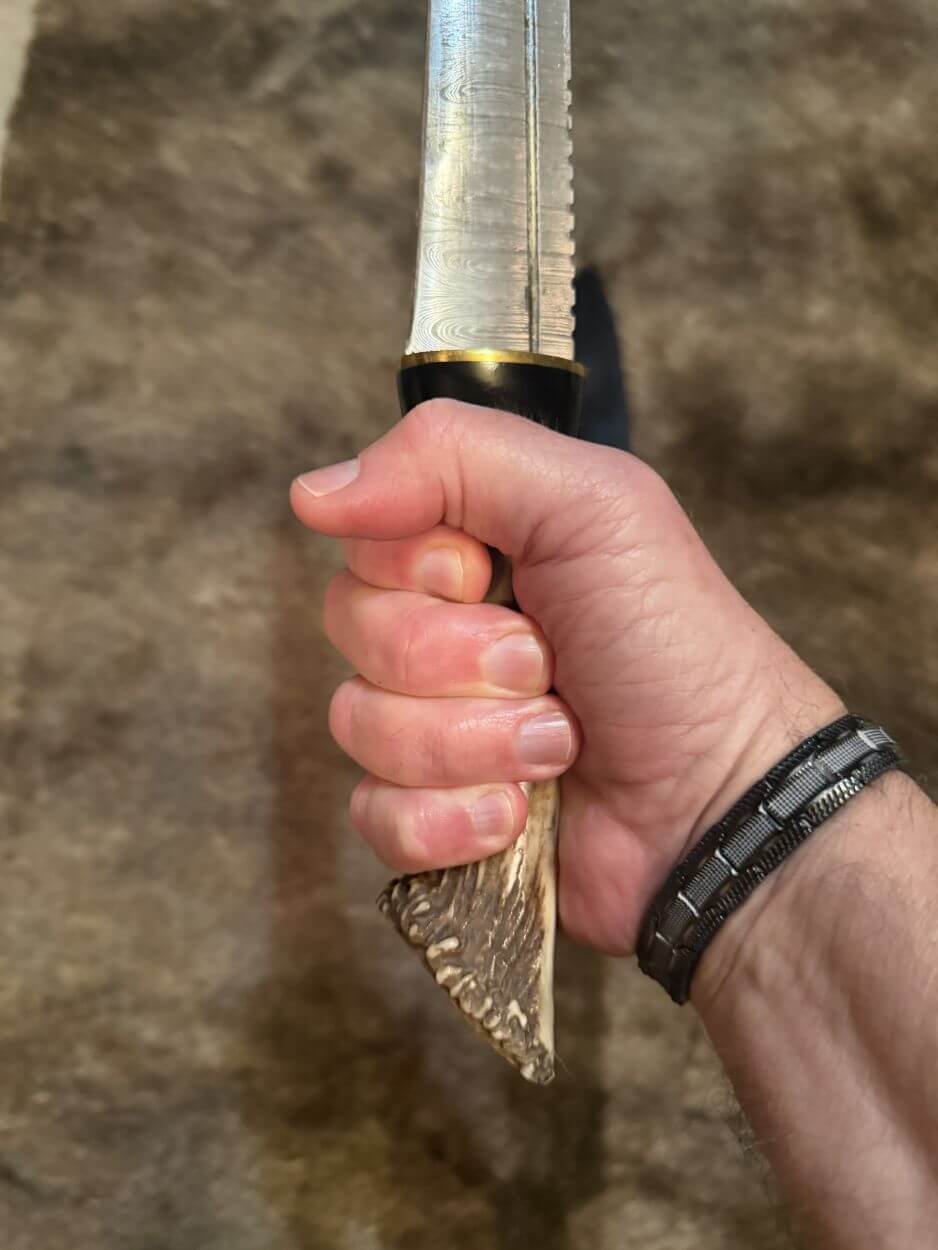 Scottish dirk with crown stag handle held in a hand, showcasing the intricate design and craftsmanship.