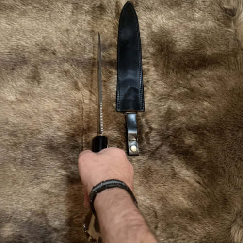 Scottish dirk with crown stag handle displayed alongside its leather sheath on fur background.