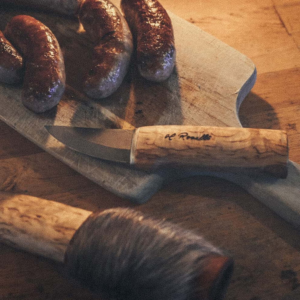 Roselli R121 The Grandfather Knife with Special Sheath beside sausages on a cutting board.