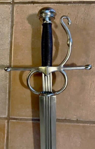 Double ringed side sword with a decorative hilt on a tiled wall